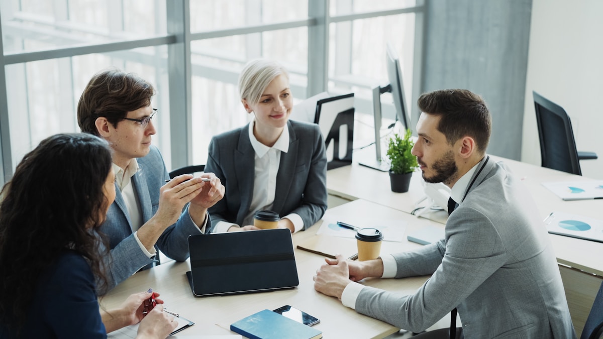 Quatre professionnels en réunion de travail autour d'une table