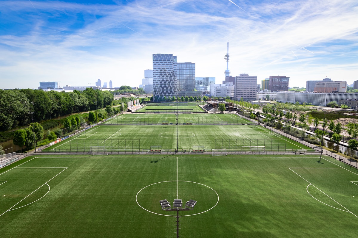 Vue aérienne de terrains de sport engazonnés en bordure d'une ville, illustration des équipements sportifs du territoire
